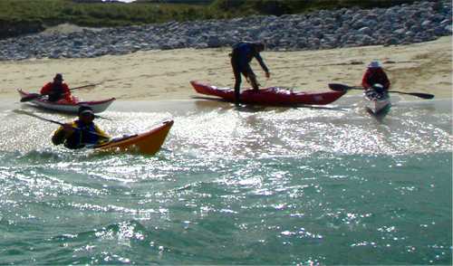Sea kayakers launching from beach